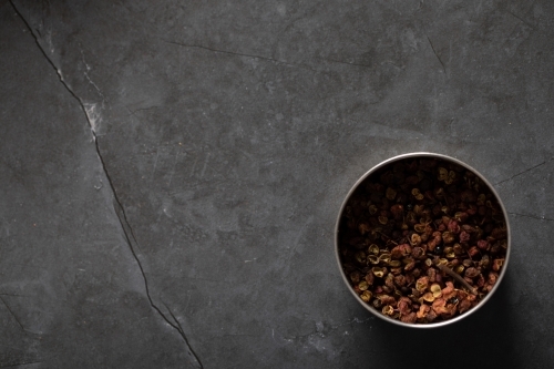 Spice tin of Sichuan pepper on dark marble background