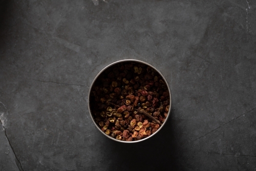 Spice tin of Sichuan pepper on dark marble background