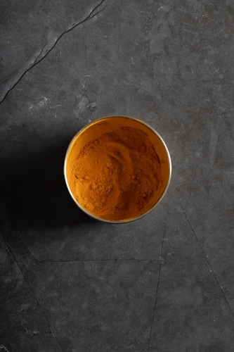 Spice tin of turmeric on dark marble table
