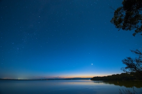 Stars in a blue night sky over water