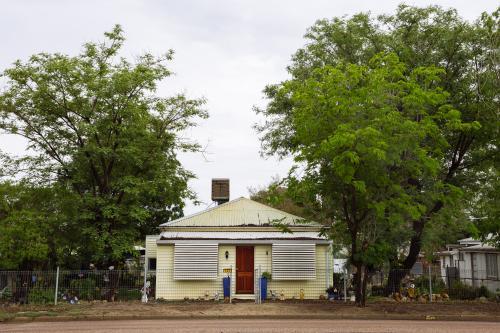 Street view of an old yellow weatherboard house in an outback town