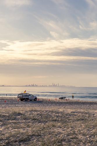 Surf Life Saving patrol ute on beach with city in background