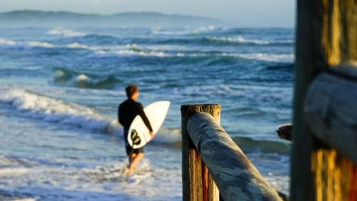Surfer with board entering the water