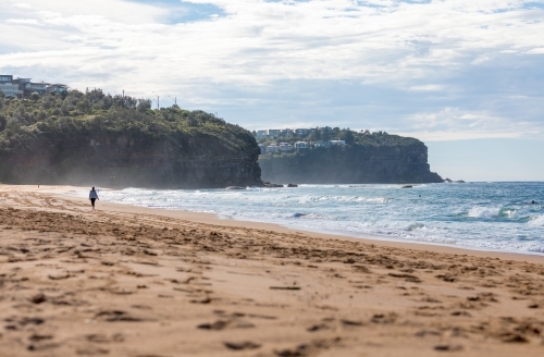 Sydney Beach scene with woman walking in distance towards the cliffs