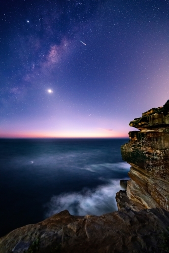 Sydney coast by night with stary universe and milky way overhead and a deep blue ocean