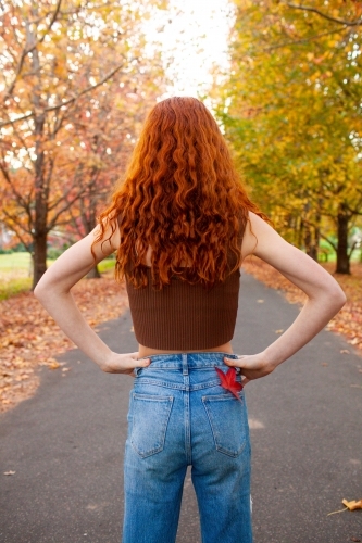 Teenage girl standing in a street lined with Autumn trees