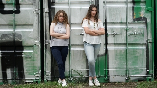 Teenage girls standing in front of container graffiti