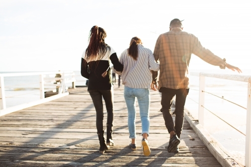 Three teenage friends walking along a jetty