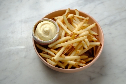 Top shot of french fries with mayonnaise in a pink bowl