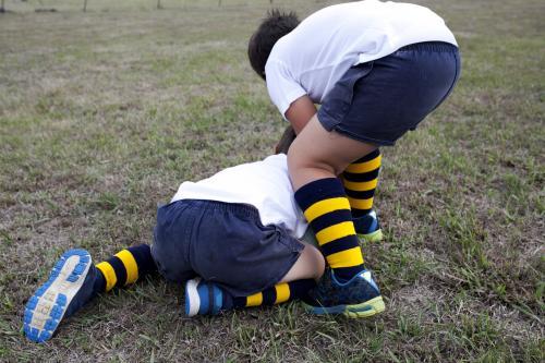 Two young school boys wrestling over a football