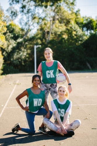 vertical shot of three young women in sports wear posing for the camera in the field on a sunny day