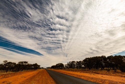 View of long straight bitumen road to horizon with dramatic cloud formations