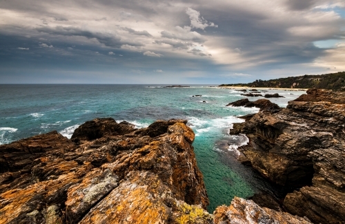View over Mystery Bay with dramatic rocks in foreground and stormy sky