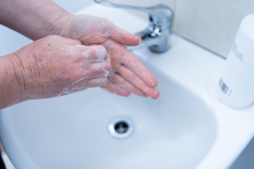 Washing hands with soap and water at basin