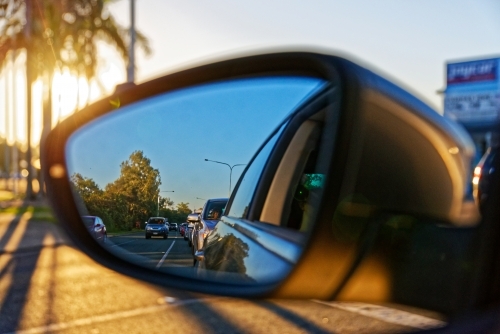 Watching traffic behind looking through the side mirror at sunset golden hour