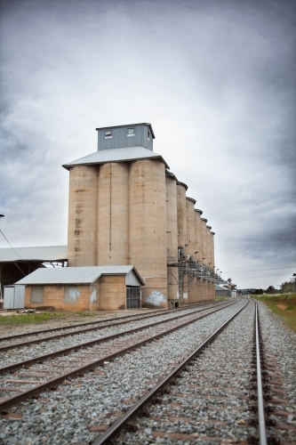 Wheat silo infrastructure beside a train line on an overcast day