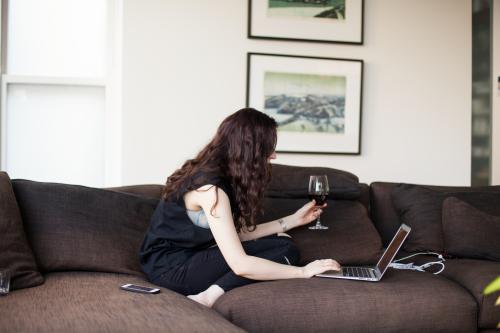 Woman multitasking. On computer, drinking wine.