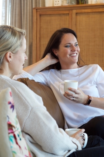 Women chatting on lounge with hot drinks