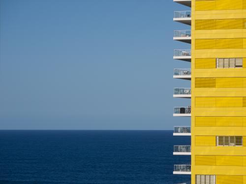 Yellow apartment building with blue sky and sea