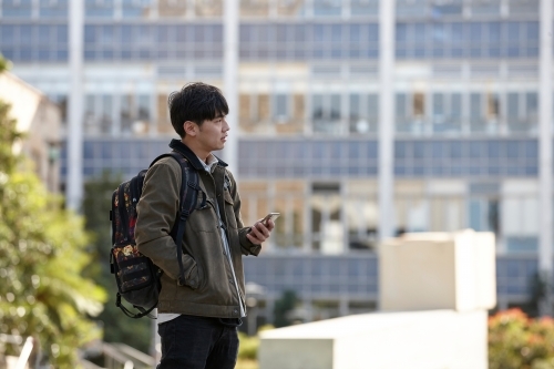 Young Asian university student using mobile phone on-campus