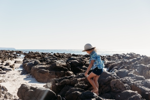Young boy in hat walking amongst rock pools