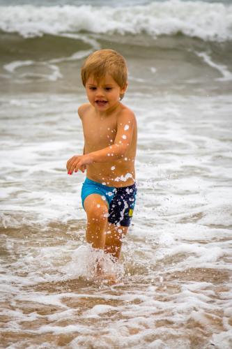 Young boy running in the surf