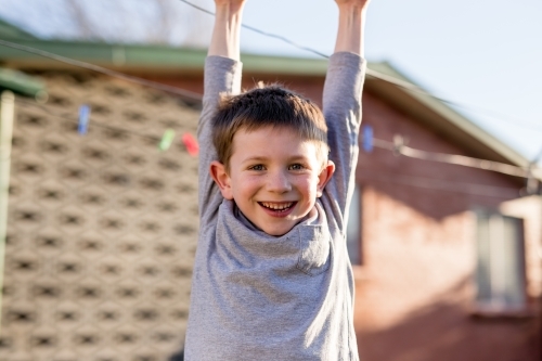 Young boy smiling hanging from washing line