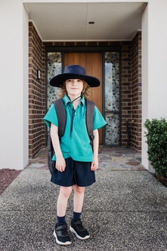 Young school boy wearing his Primary Public School uniform standing outside the front of his house