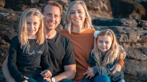 Young family of four portrait at sunrise on beach