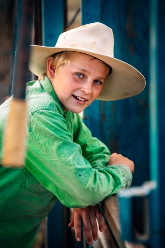 Young farmer leaning on the fence at the yards