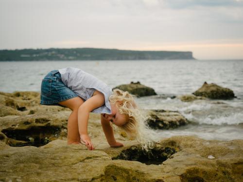 Young girl bending to look in rockpools at the beach