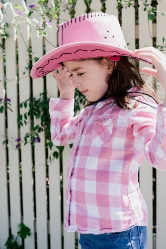 Young girl dressed up as a cowgirl wearing a pink akubra hat and pink checkered shirt