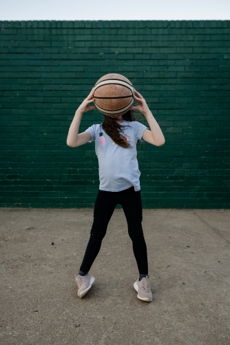 Young girl holding up a basketball in front of her face