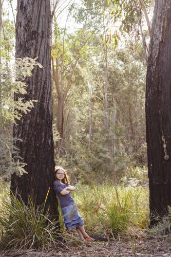 Young girl leaning against large tree