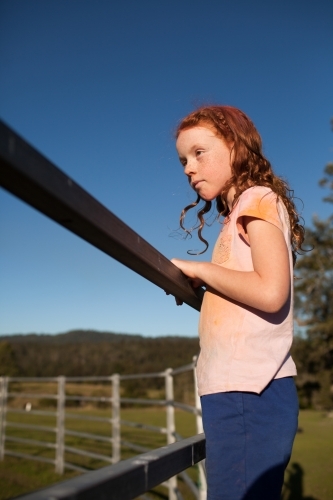 Young girl looking over a metal fence