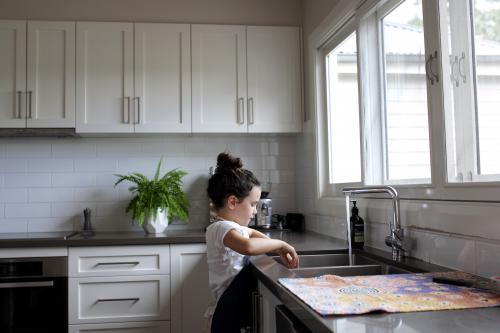 Young girl standing at sink in kitchen
