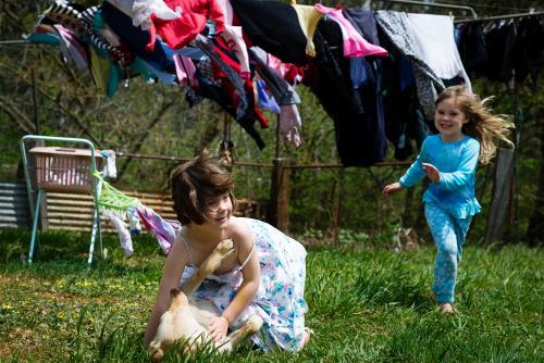 Young girls & their dog play under the clothes line