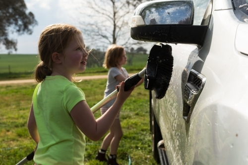Young girls washing a car for pocket money