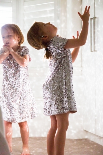 Young girls wearing sparkly dresses playing with the reflected light