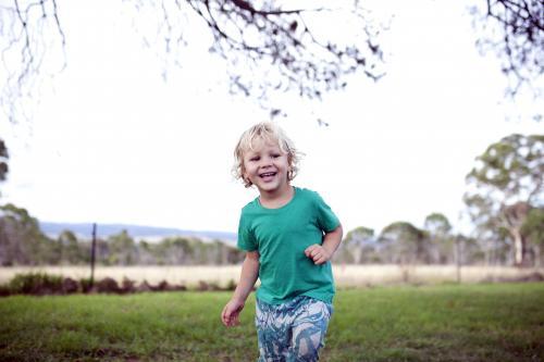 Young happy boy wearing a green t-shirt playing outside