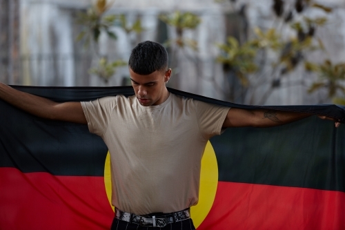 Young Indigenous Australian man holding Aboriginal flag