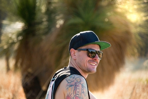 Young man with tattoos smiling outdoors