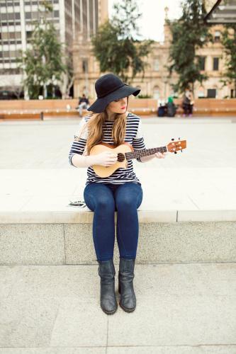 Young woman playing a ukulele on city street