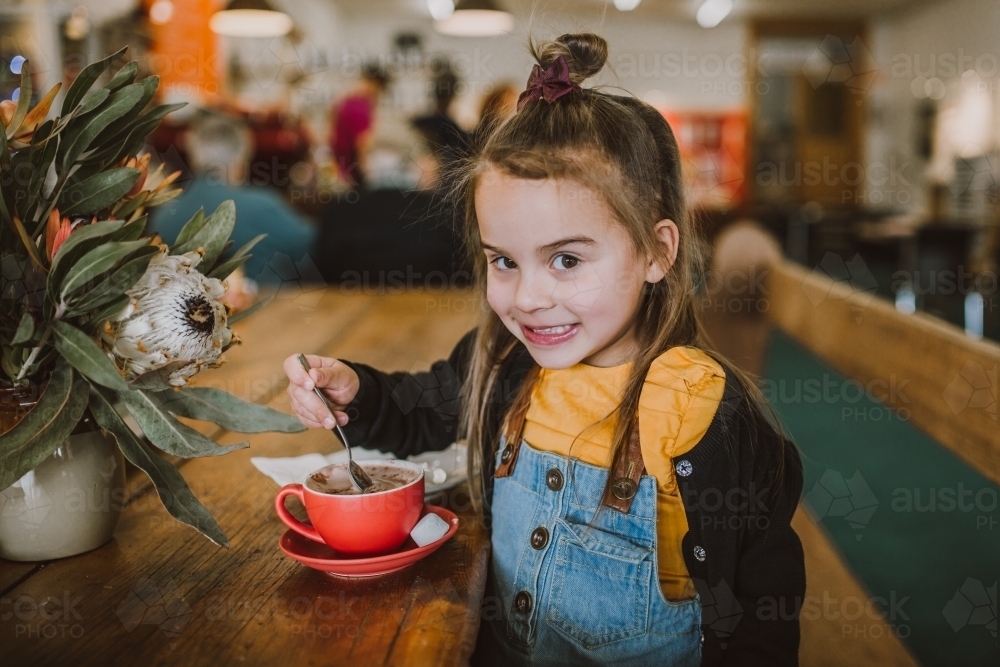 Little girl drinking a hot chocolate - Australian Stock Image