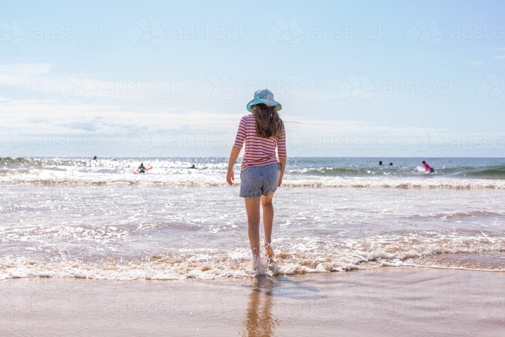 10 year old girl standing in the waves at the beach - Australian Stock Image