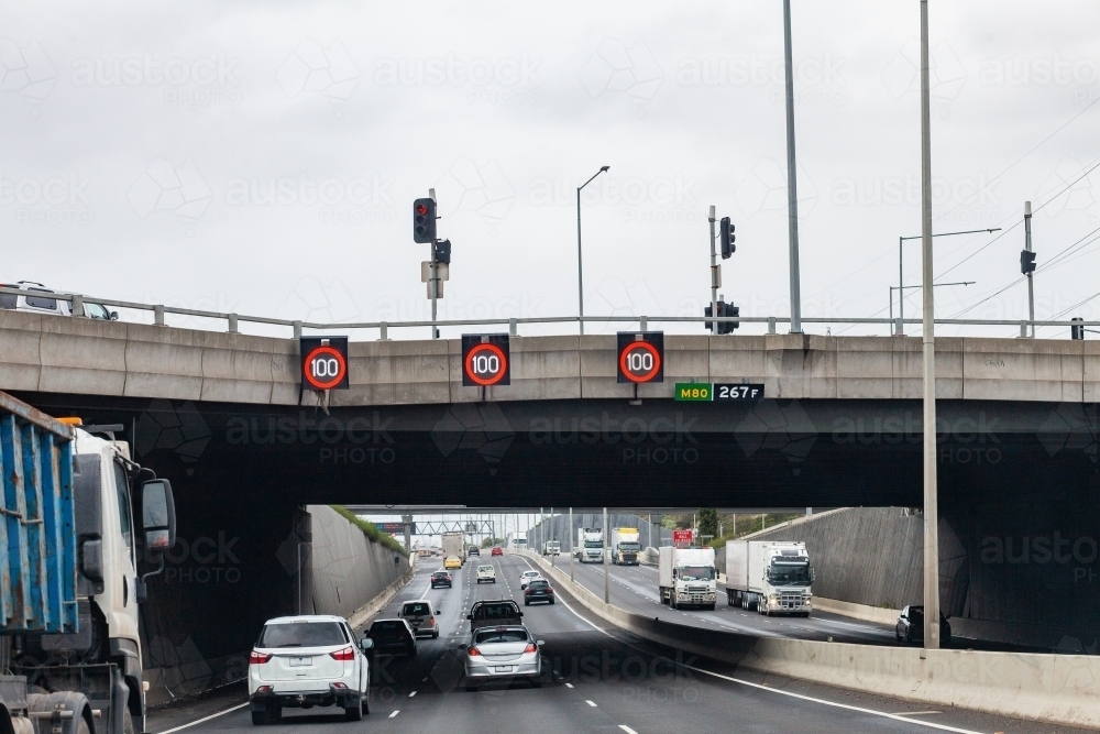 100 speed limit sign on overhead bridge on road into Melbourne - Australian Stock Image