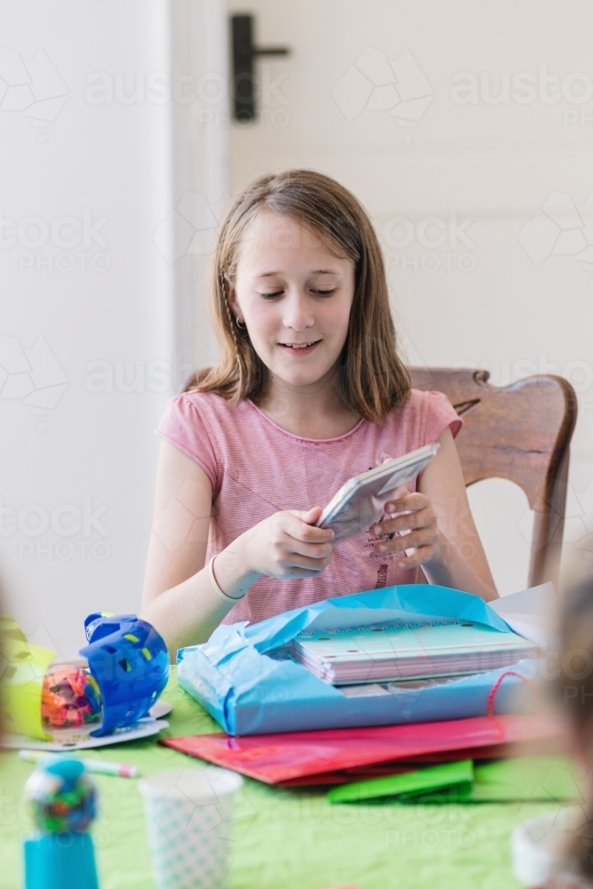 12 year old girl opening birthday presents at her birthday party - Australian Stock Image