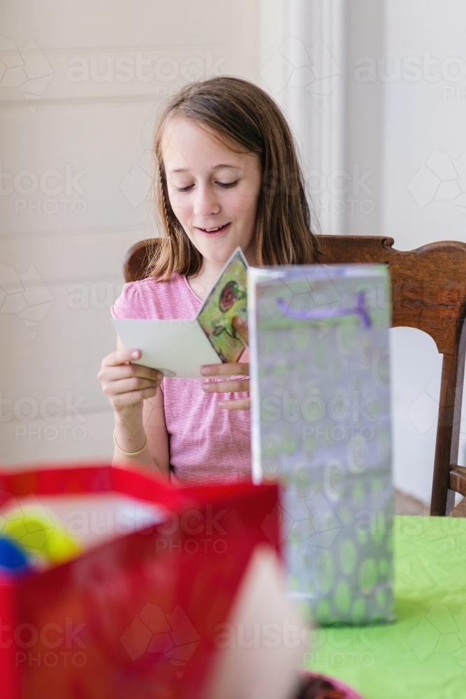 12 year old girl reading the card before opening presents at her party - Australian Stock Image