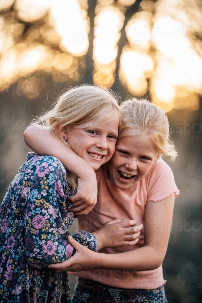 2 girls hugging and smiling with each other - Australian Stock Image