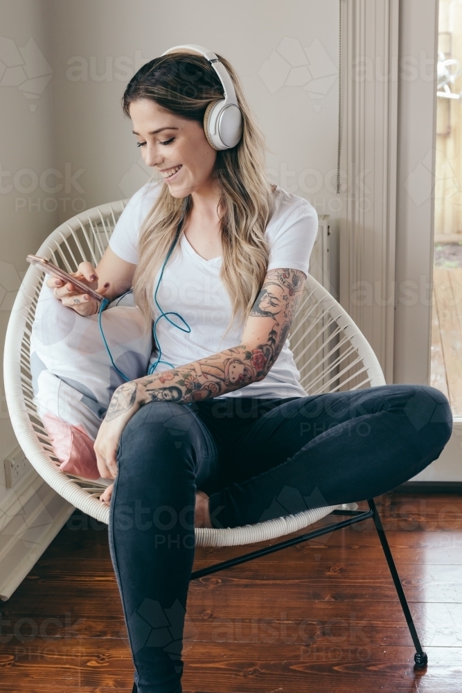 20 something girl listening to a podcast with headphones - Australian Stock Image
